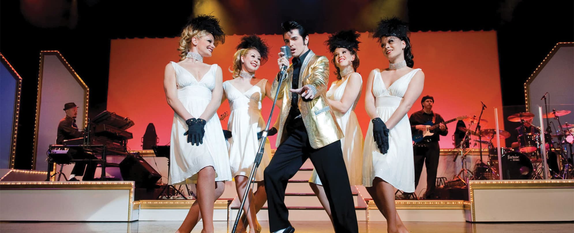 An Elvis Presley impersonator and female performers on stage at Dick Clark's American Bandstand Theater.