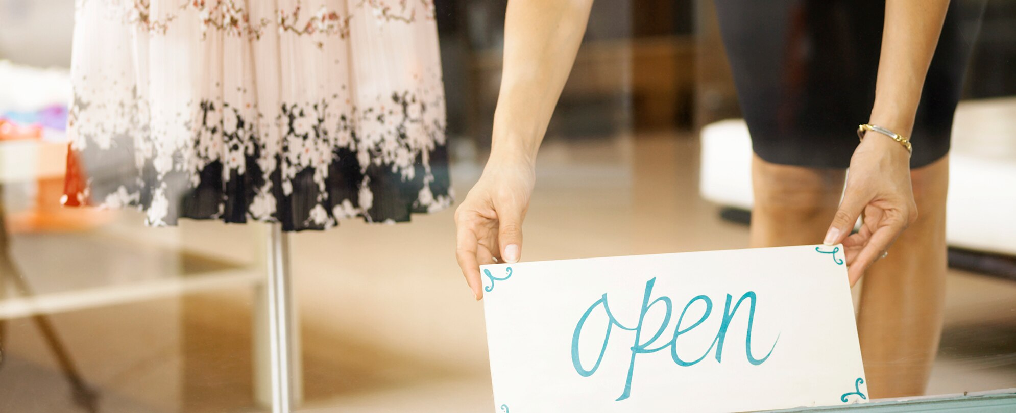 Two hands hold an "open" sign at boutique on Park Ave in Winter Park, Florida.