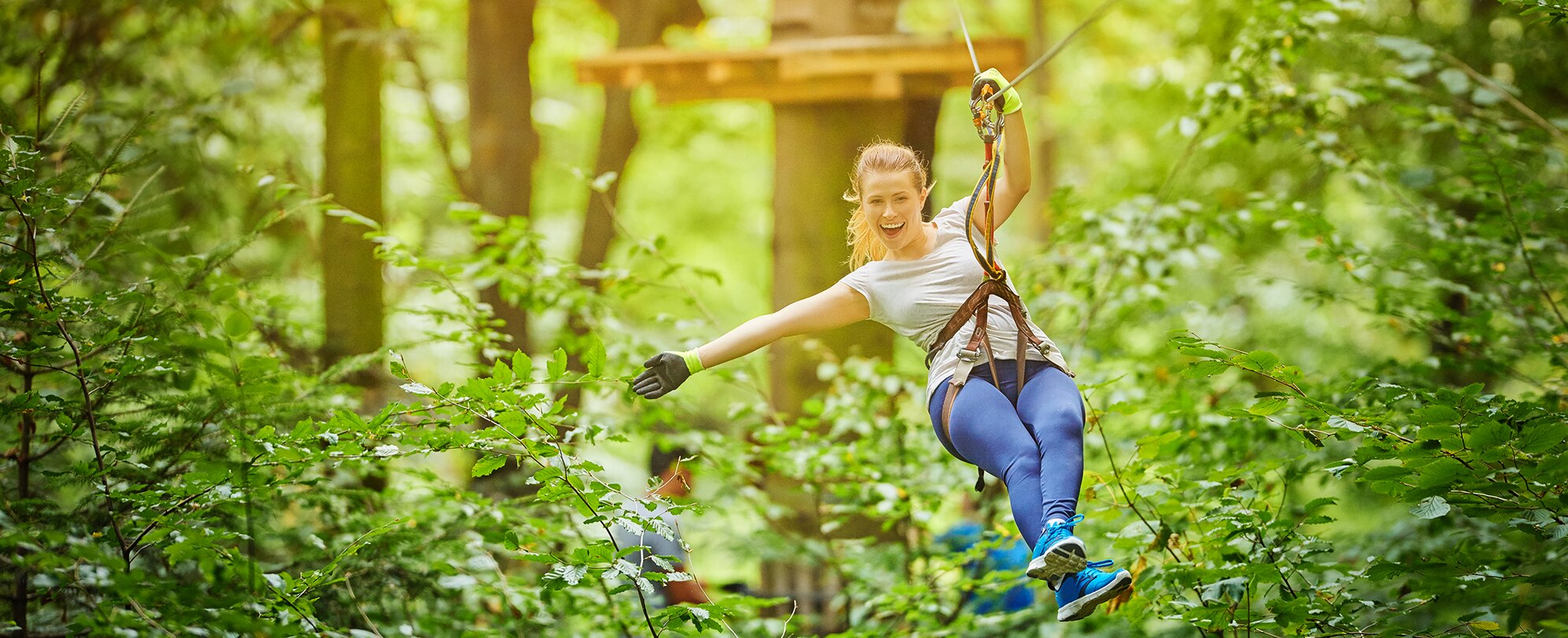 A woman smiles and holds her arm out while zip lining in Orlando, Florida.