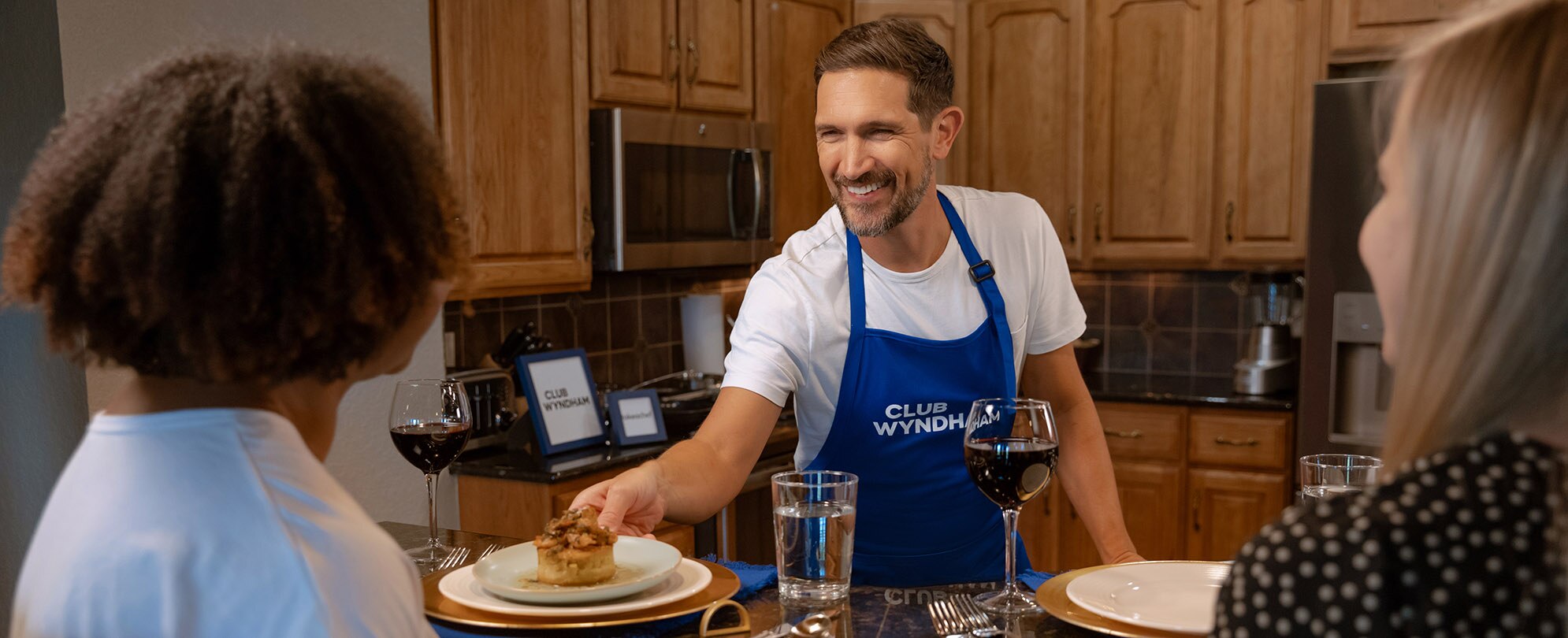 2 women get served a meal by a private chef in their Club Wyndham resort suite.