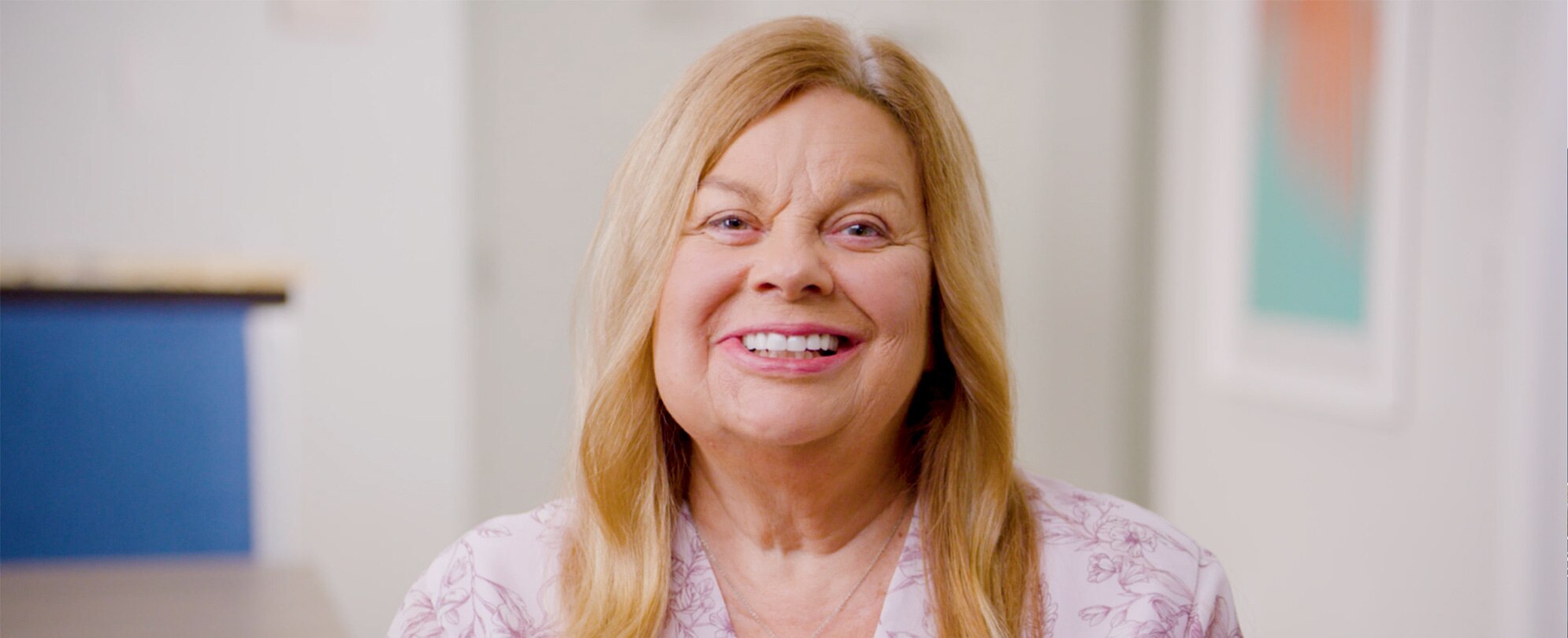 A timeshare owner in a pink shirt smiling directly into the camera 