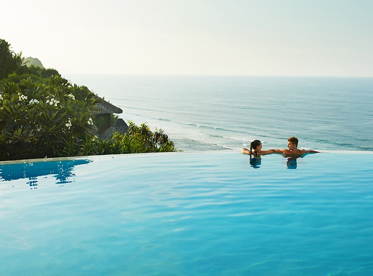 Couple on edge of infinity pool overlooking ocean on their Club Wyndham vacation.