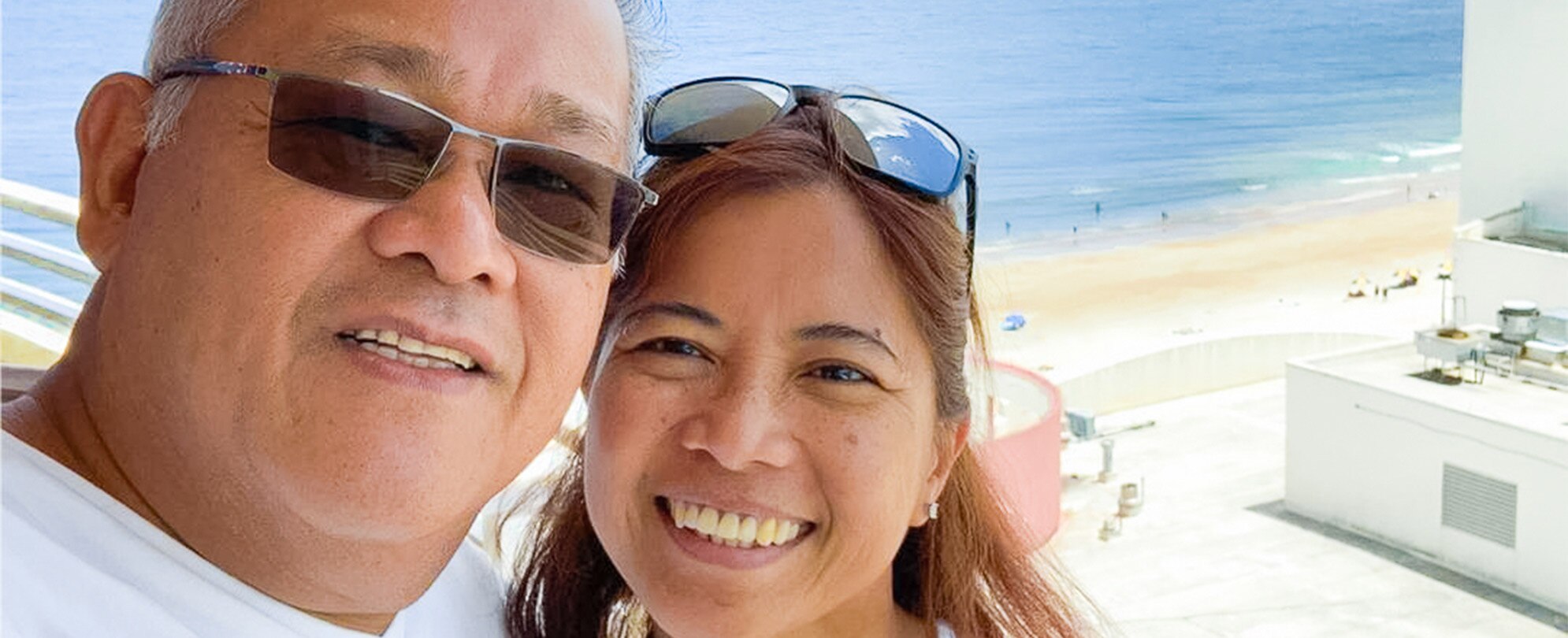 A smiling couple takes a selfie together from their suite balcony overlooking the beach at Club Wyndham Ocean Walk in Daytona Beach, Florida