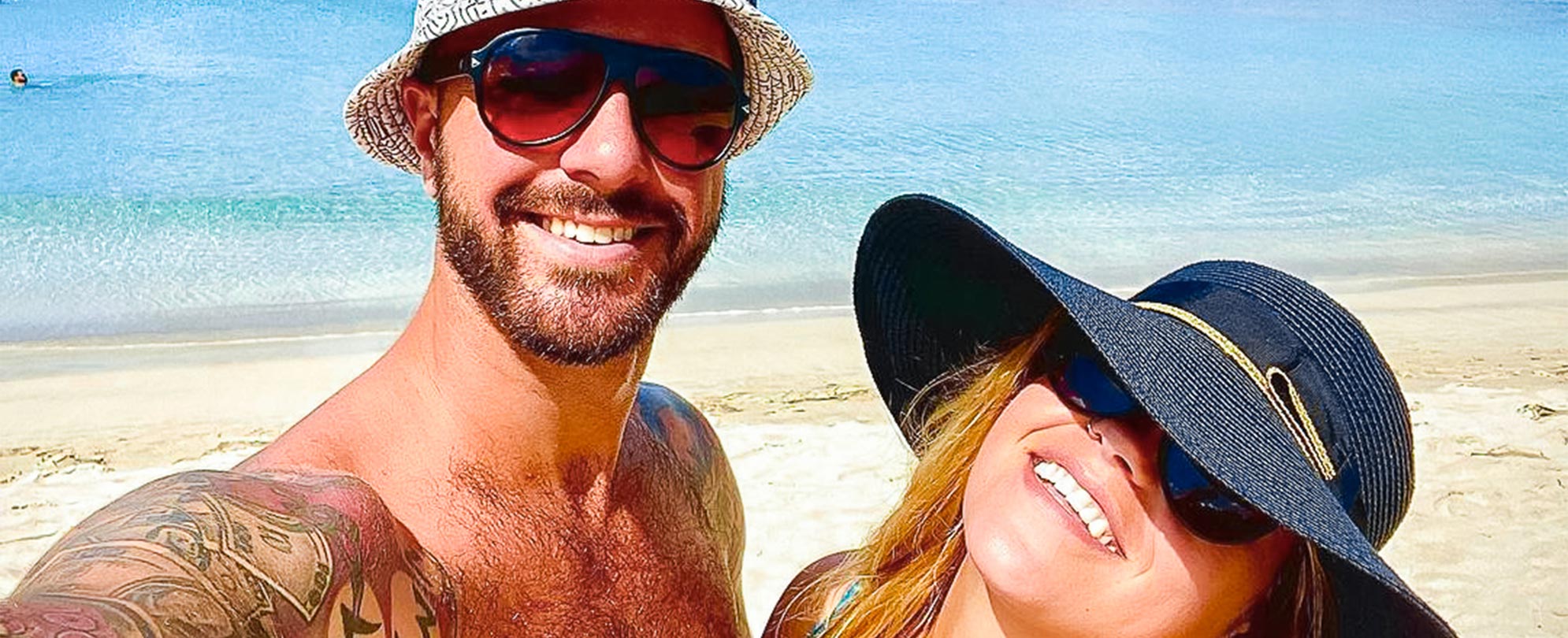 A couple wearing hats and swimsuits pose together for a selfie at Magens Bay in St. Thomas, U.S. Virgin Islands