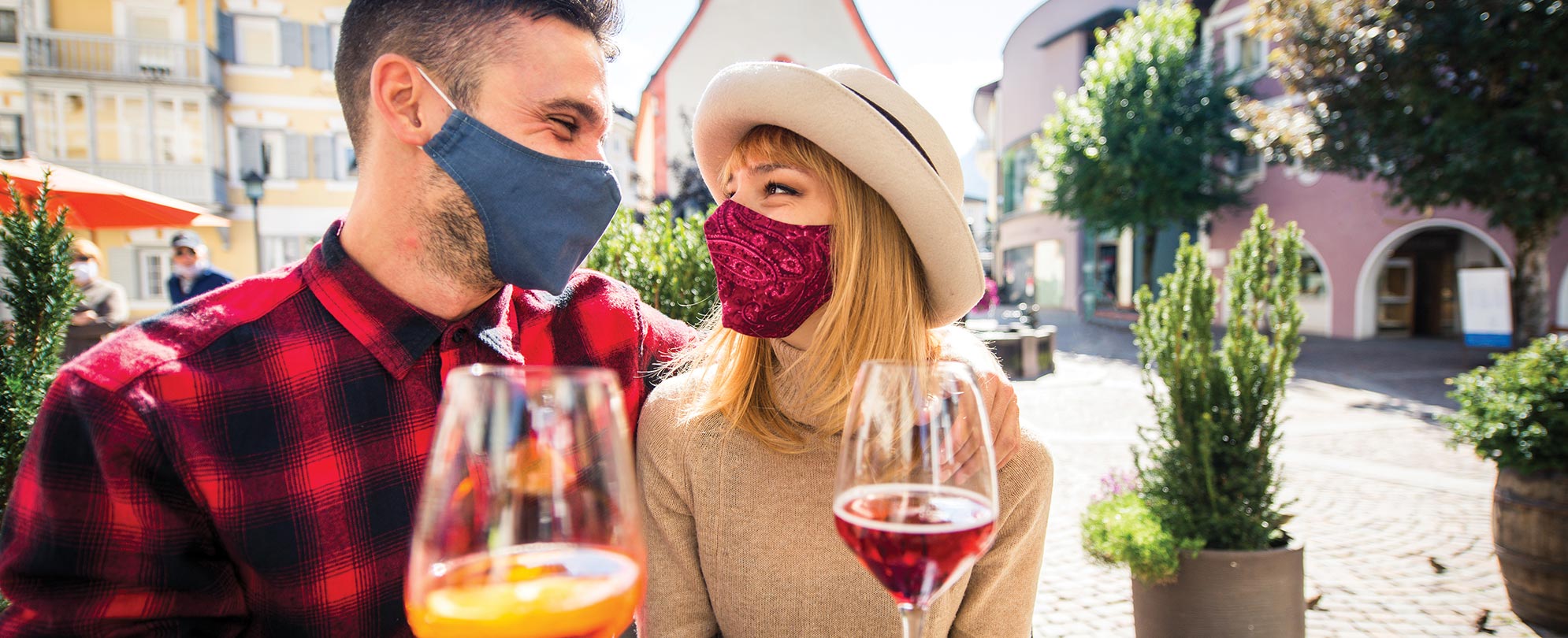 Masked man and woman drinking wine in a top drinking destination
