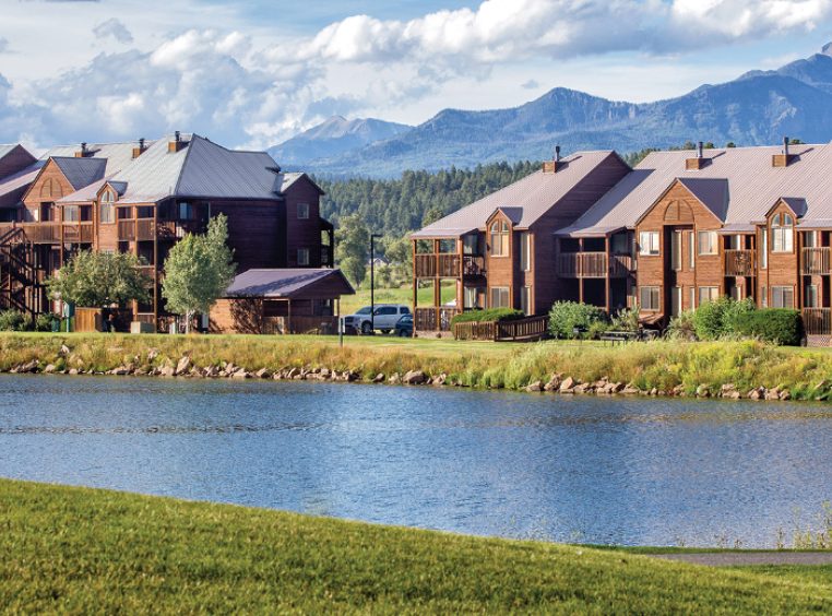 The exterior of WorldMark/Club Wyndham Pagosa, a Colorado timeshare resort surrounded by a lake and mountains.